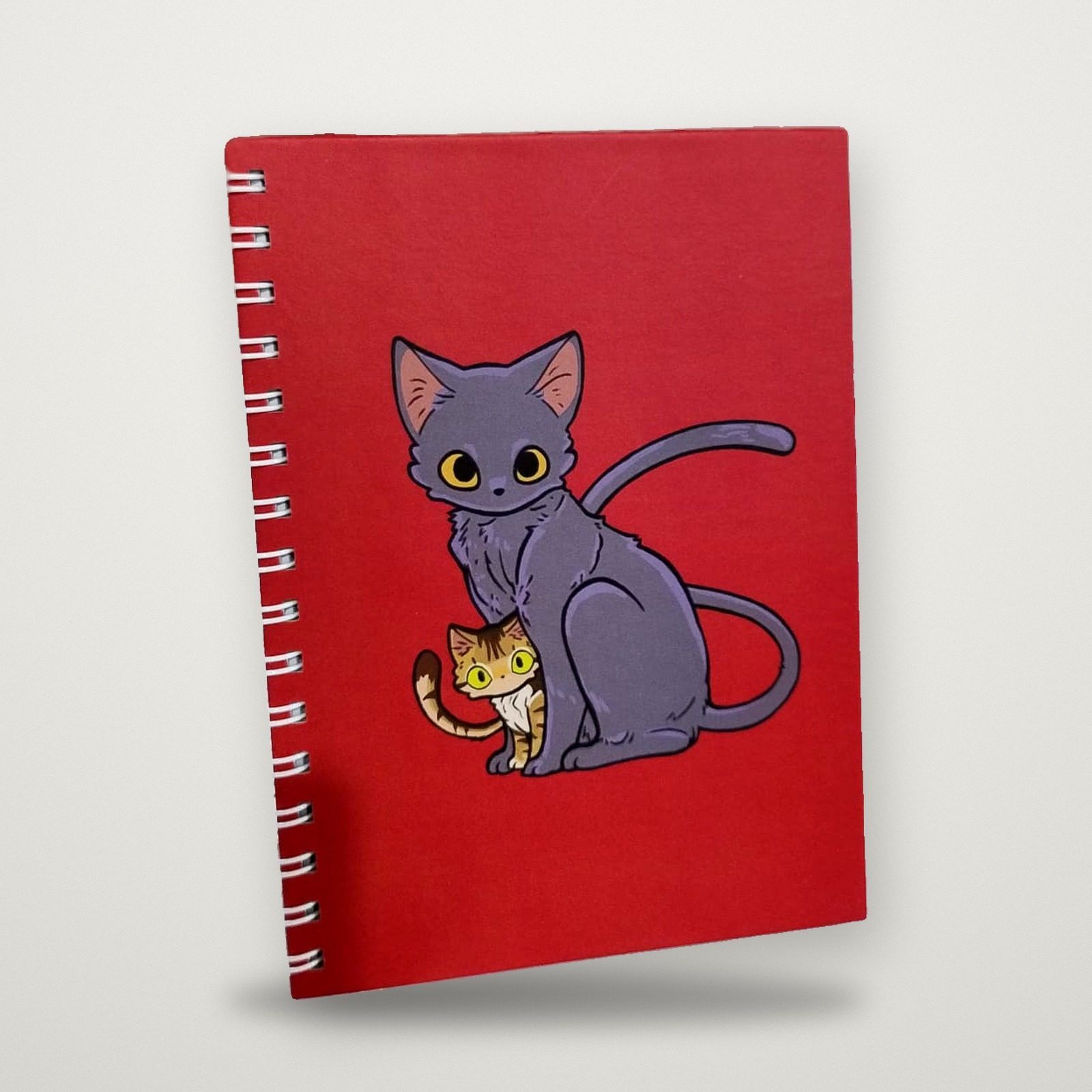 Cuaderno rojo anillado con ilustración de gatos en la tapa